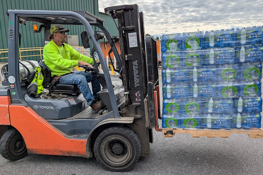 Profile employee volunteer with forklift of bottled water